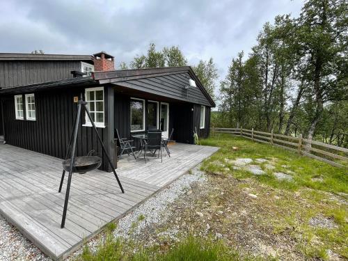 una pequeña casa negra con terraza de madera en Sigurdhytta, en Al