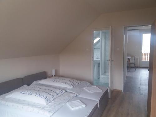 um quarto com uma cama com lençóis brancos e almofadas em Egervári Béres Vendégház-Tetőtéri apartman em Egervár