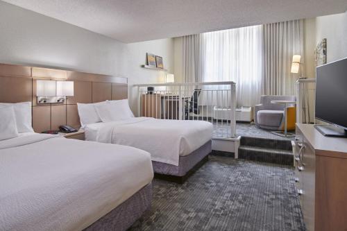 a hotel room with two beds and a flat screen tv at Courtyard Columbus Downtown in Columbus