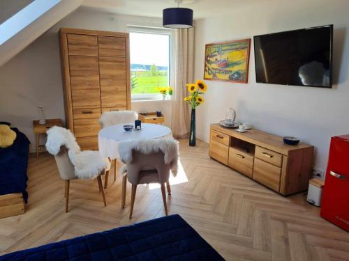 a living room with a table and chairs and a tv at Apartament Cztery Strony Mazur in Ryn