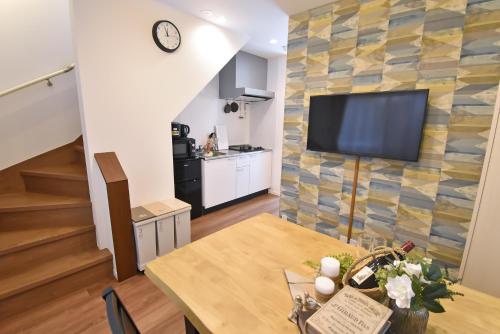 a living room with a table and a television on a wall at ID STAY Haneda in Tokyo