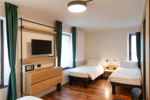 a hotel room with two beds and a television at Hotel SALEI in Ghigo