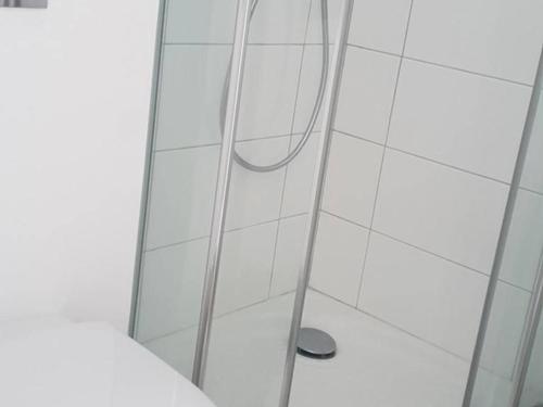 une douche avec une porte vitrée dans une salle de bain dans l'établissement Appartement T2 avec Balcon, Centre de Cauterets, Près des Thermes et Remontées Mécaniques - FR-1-234-121, à Cauterets