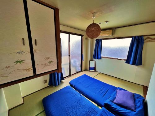 Un dormitorio con una cama azul y una ventana en Peace House Sakura, en Kioto