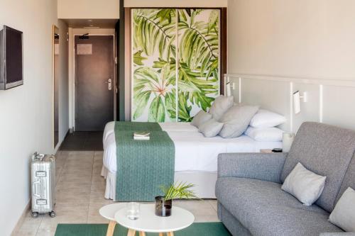 リョレート・デ・マルにあるAQUA Hotel Bertran Parkのベッドとソファ付きのホテルルーム