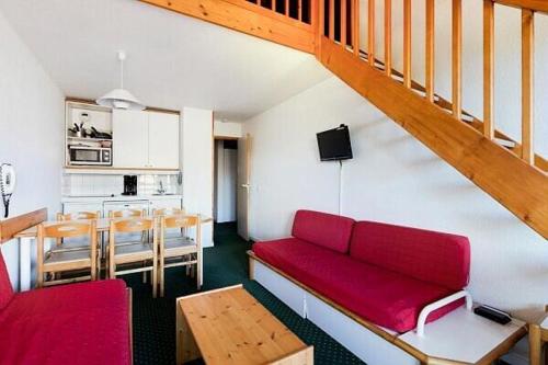 un salon avec un canapé rouge et une cuisine dans l'établissement Residence Le Hameau du Sauget - maeva Home, à Les Coches