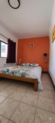 une chambre avec un lit avec un mur orange dans l'établissement Gîte 2 - LE RAZAL, à Vallon-Pont-dʼArc
