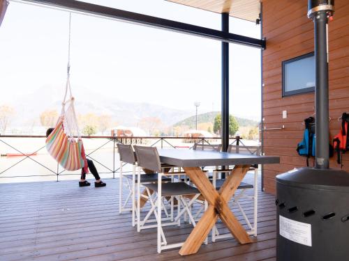 a wooden deck with a table and chairs and an umbrella at GLAMP ELEMENT(グランエレメント） in Maibara