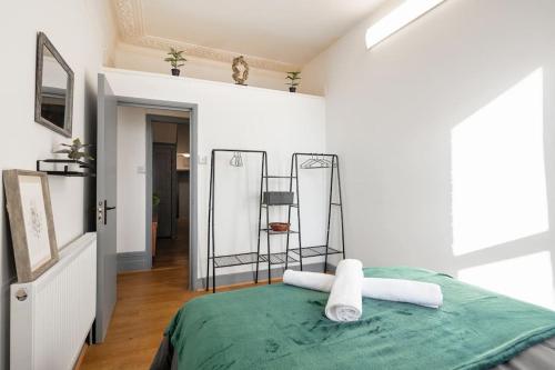 a bedroom with a green bed with towels on it at 2A - Bright & Airy 2 Bed Flat - 20 Mins to Central in London