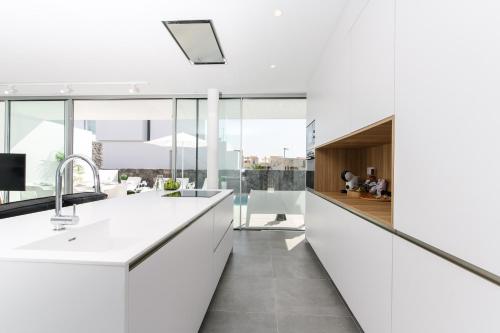 an open kitchen with white countertops and glass walls at Villa Moada Ocean Breeze in Callao Salvaje