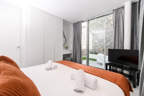 a white bedroom with a bed and a television at Villa Moada Ocean Breeze in Callao Salvaje