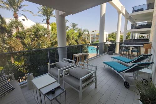 a balcony with chairs and tables on a house at Garden and Pool at Royal Park Eilat in Eilat