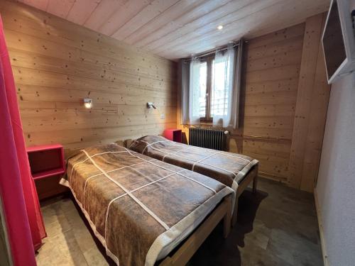 a large bed in a room with wooden walls at GENTIANES 2 - Appartement centre village et proche pistes de ski - Wifi in La Clusaz