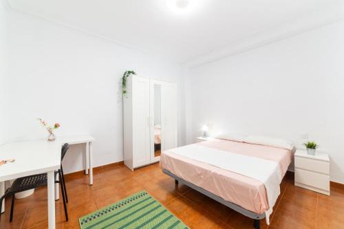 Habitación blanca con cama y escritorio en Casa Maruchi - Apartamento en Almería