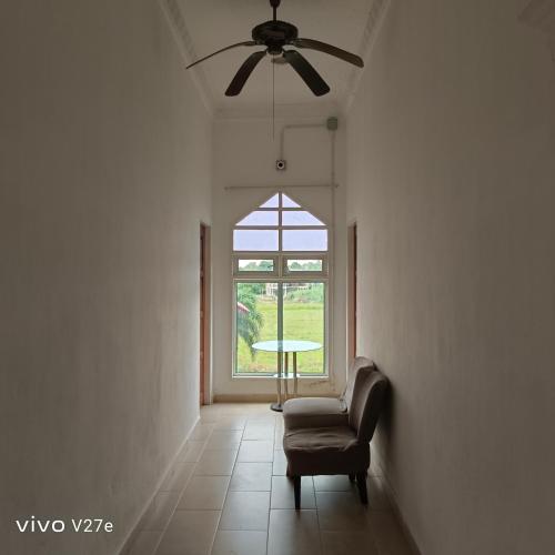 a living room with a chair and a ceiling fan at Flora Inn in Kota Bharu