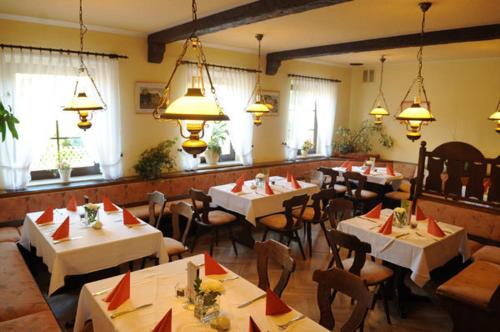 un restaurante con mesas y sillas blancas y ventanas en Beierleins Hotel & Catering GMBH en Reichenbach