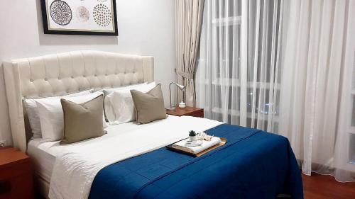 una camera da letto con un grande letto bianco e un vassoio di Lucky Tower Residence 2BR Top Floor Condo a Giacarta