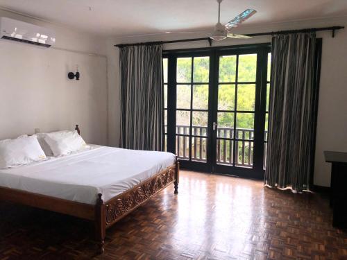 a bedroom with a bed and a large window at Wayside Beach Apartments in Diani Beach