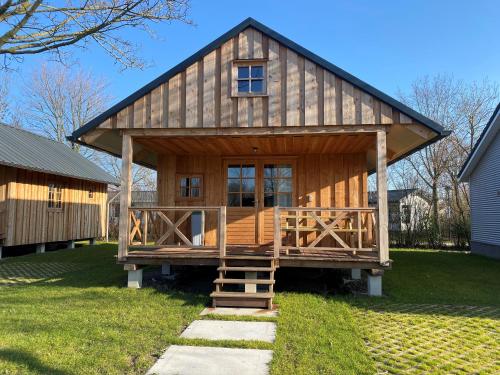 a large wooden cabin with a large deck at Camping de Uitwijk in De Heen
