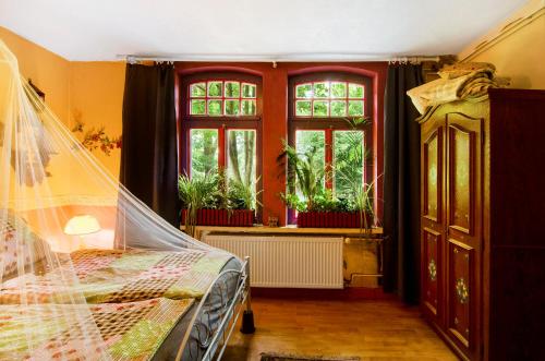 een slaapkamer met een bed en ramen met planten bij Fairy Cottage in Rhauderfehn