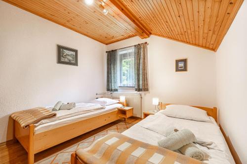 2 camas en una habitación con techo de madera en House Mavko Near Lake Cerknica, en Grahovo