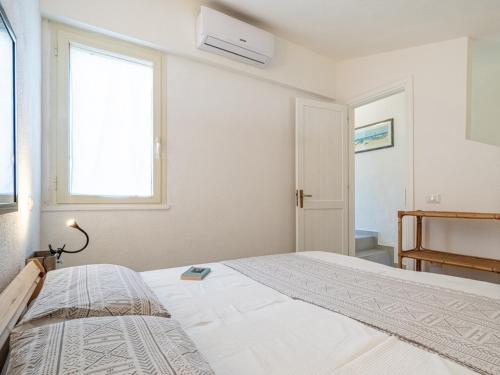 a white bedroom with a bed and a window at Casa Flaminia Villasimius in Villasimius