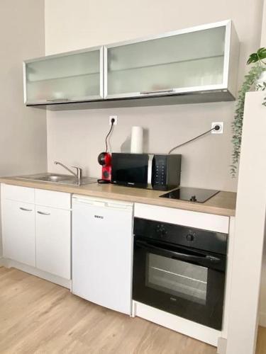 une cuisine avec des armoires blanches et un four noir dans l'établissement Appartement au coeur de Nice pour 4 - Clim & Wifi, à Nice
