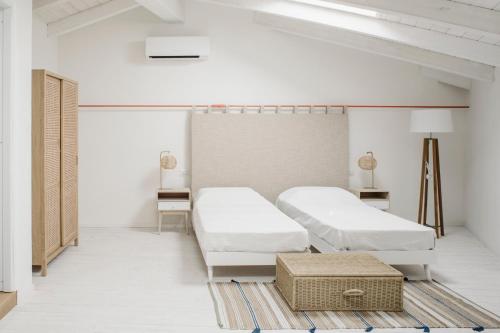um quarto branco com duas camas e uma mesa em AltaMarea - Ampi spazi in Centro storico em Carloforte