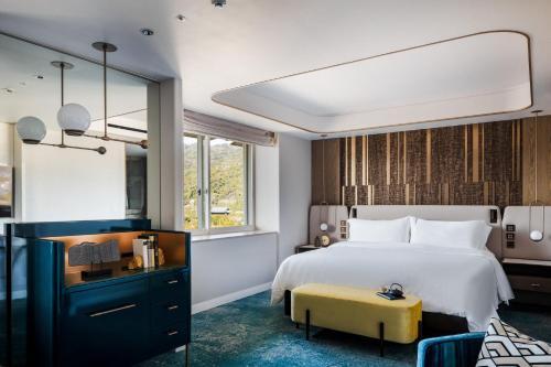 a bedroom with a large bed and a yellow stool at The Westin Miyako Kyoto in Kyoto