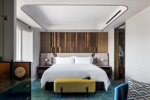a bedroom with a large white bed and a yellow stool at The Westin Miyako Kyoto in Kyoto