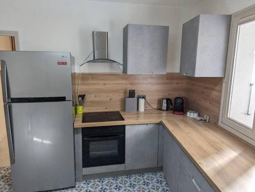 a kitchen with a white refrigerator and a wooden counter top at Appartement Cosy centre ville in LʼIsle-sur-la-Sorgue