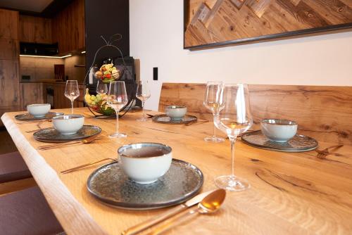 a wooden table with wine glasses and a table with a bowl and a cup at Penthouse Suite by Brugger in Taxenbach