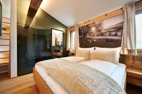 a bedroom with a large bed with a painting on the wall at Penthouse Suite by Brugger in Taxenbach