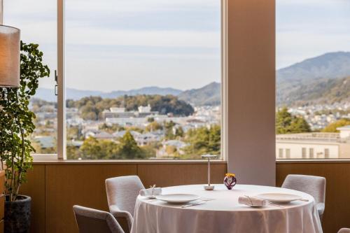 a table and chairs in a room with a large window at The Westin Miyako Kyoto in Kyoto