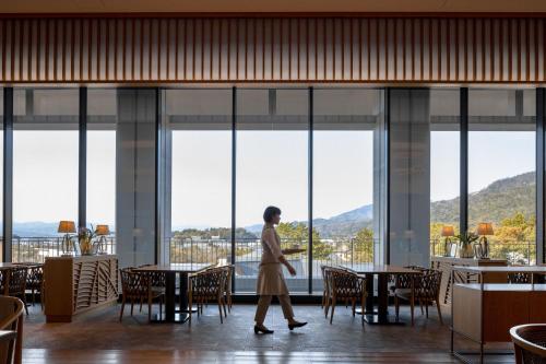 a woman walks through a restaurant with large windows at The Westin Miyako Kyoto in Kyoto