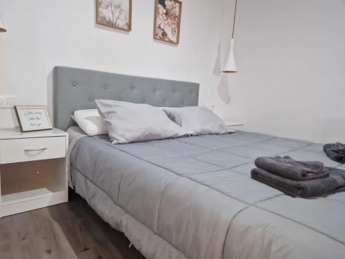 a white bedroom with a bed and a night stand at Apartamento Comarca de Haro in Haro