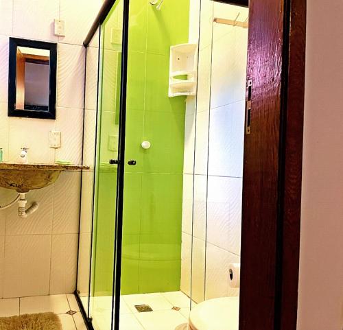 a green bathroom with a toilet and a shower at L&M Housing Apartamentos y casa in Búzios