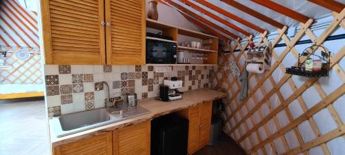 a small kitchen with wooden cabinets and a sink at Jurtarelax in Kozármisleny
