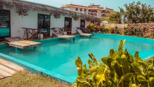 una piscina con panchine e una casa sullo sfondo di Tropicana Garden a Kendwa