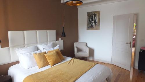 a bedroom with a large white bed with yellow pillows at Le Four à Pain du Domaine de Choisy in Abzac
