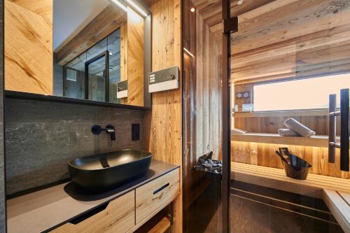 a bathroom with a black sink and wooden walls at Penthouse Suite by Brugger in Taxenbach