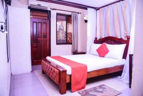 a bedroom with a bed with a red blanket on it at Lambada Holiday Resort Mombasa in Mtwapa