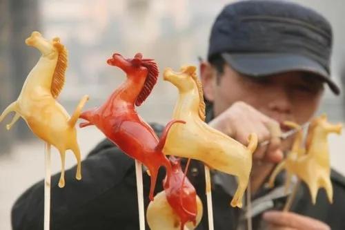 a man holding four toy horses on a stick at The East Hotel-Very close to the Drum Tower,The Lama Temple,Houhai Bar Street,and the Forbidden City,There are many old Beijing hutongs around the hotel Experience the culture of old Beijing hutongs,Near Exit A of Shichahai on Metro Line 8 in Beijing