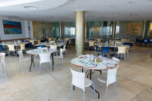 uma sala de jantar com mesas e cadeiras brancas em Adi Hotel em Eilat
