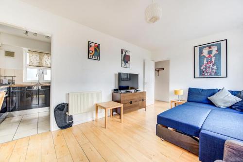 a bedroom with a blue bed and a kitchen at GuestReady - Penthouse Flat in Trendy Peckham in London