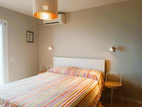 a bedroom with a bed with a striped bedspread at Villa Service - Coral III in El Vendrell