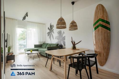 a living room with a table and a surfboard on the wall at Hawaje apartament przy plaży - 365PAM in Sianozety