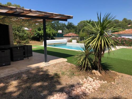 - une piscine avec un palmier dans la cour dans l'établissement Villa 3 chambres avec piscine privée, à Bagnols-en-Forêt