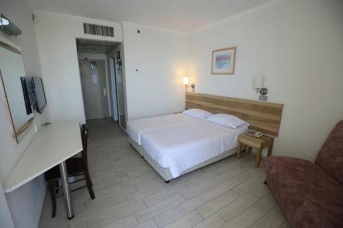 a bedroom with a white bed and a desk at Adi Hotel in Eilat