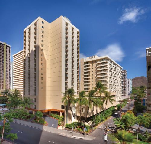 a tall white building with palm trees in a city at Hyatt Place Waikiki Beach in Honolulu